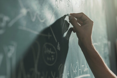 Professor writing mathematical formulas on the chalkboard